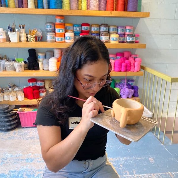 Me painting a clay cup at a pottery studio